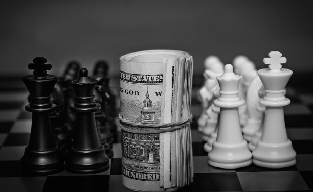 特写扭曲美元站在棋盘之间的一个白棋和黑棋队。概念上的照片。团队游戏。竞争。图片下载