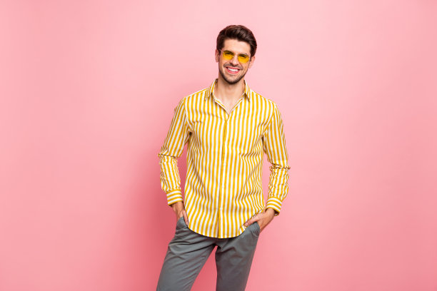 英俊的男子手在口袋的照片夏天晴天穿太阳眼镜时尚的条纹衬衫裤子孤立的粉红色柔和的颜色背景图片下载