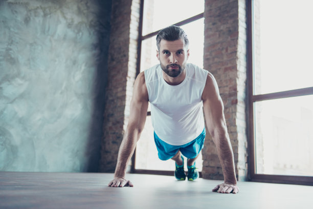 照片的大男子主义男子显示客户如何做俯卧撑和平板正确的手倾斜地板运动服坦克顶部训练房室内工作室窗户图片下载