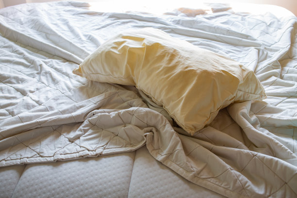 洗衣，使用象牙枕头，白色床上使用白色皱巴巴的床单，选择性聚焦，卧室清洁概念图片下载