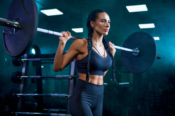 女子在健身房用杠铃训练。图片下载