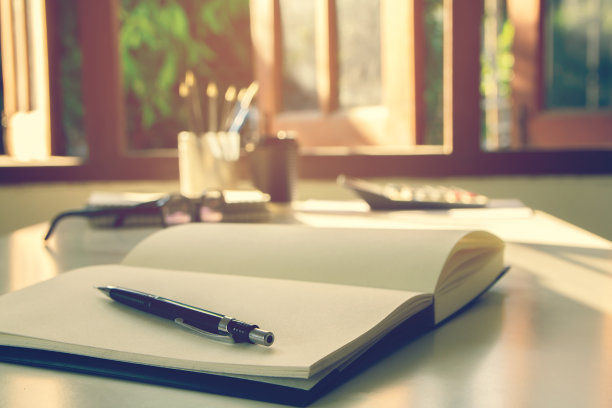 黑色铅笔在打开的书与眼镜和计算器复古色调和日落光背景图片下载