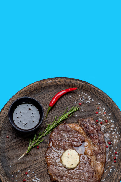蓝底木盘上的烤多汁牛排。俯视图图片下载