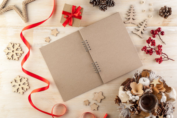 在一张木制桌子上，打开一个黑色的笔记本，周围是手工制作的圣诞装饰品图片下载