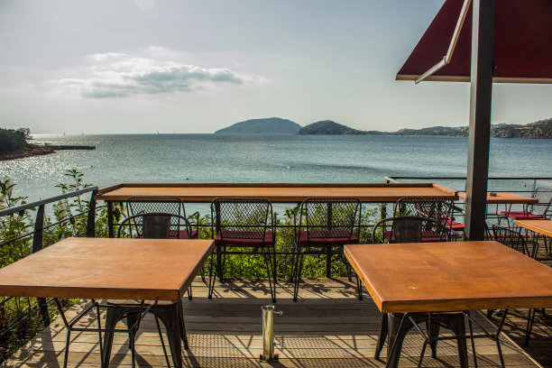 室外露台咖啡厅外部设计阳台空间，采用空木桌椅家具，靠近海滨南岸自然景观图片下载