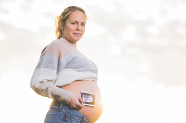 一位孕妇正拿着她宝宝的照片，超声波照片。在户外。图片下载