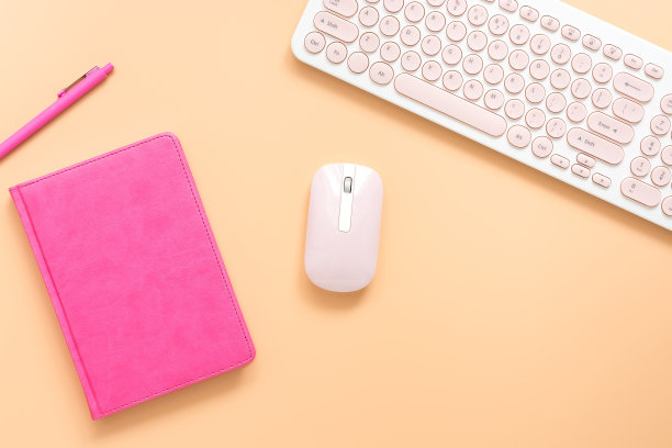 粉色笔记本，钢笔，键盘和鼠标在一个柔和的背景。女性的工作空间。俯视图，平放。图片下载