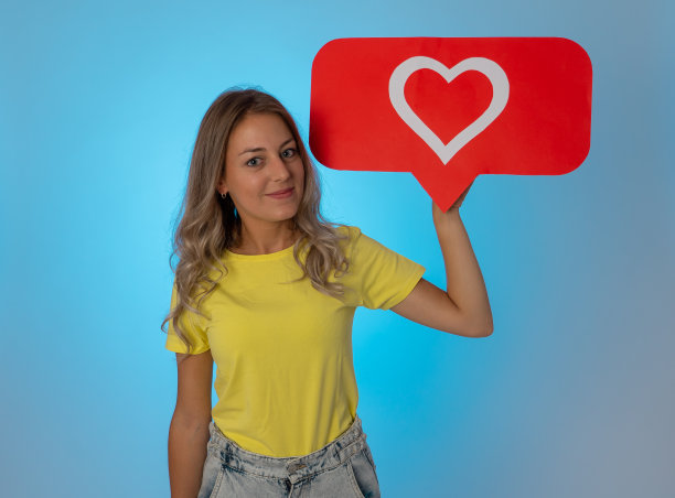 有魅力的女人拿着心形象征喜欢和爱的社交媒体通知图标与粉丝在网上高兴。女孩喜欢在情人节收到留言。沉迷于社交媒体和社交网络。图片下载