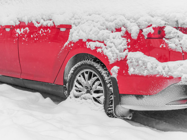 雪下的红色汽车特写。下雪，坏天气冬天概念。图片下载