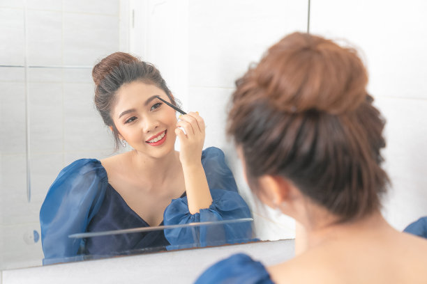 一个美丽的亚洲女人在镜子前化妆的肖像。图片下载