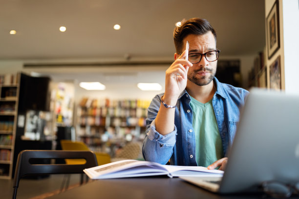 年轻的学生用笔记本电脑在大学图书馆学习图片下载
