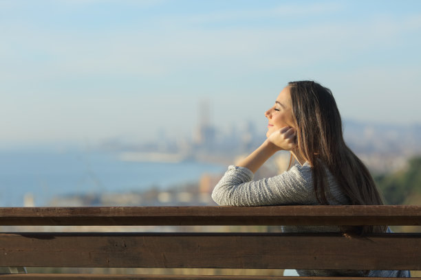 放松的女人坐在长椅上闭着眼睛图片下载