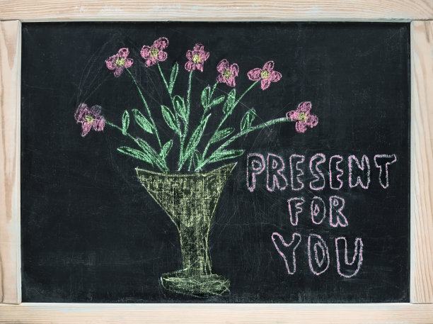 手绘涂鸦可爱的彩色花瓶与鲜花在黑板上与祝愿“礼物给你”。俯视图，文本复制空间。生日，3月8日，情人节的有趣背景图片下载
