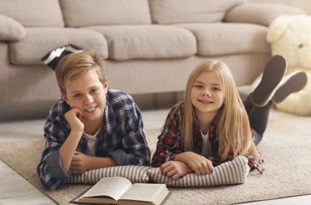 男孩和女孩一起躺在地板上看书图片下载