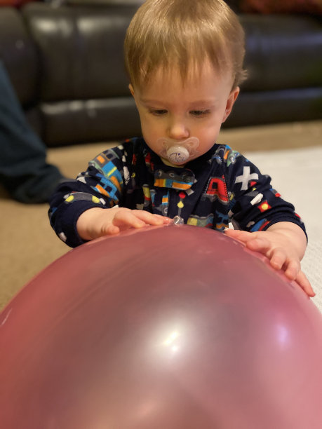 蹒跚学步的孩子在玩一个大气球图片下载