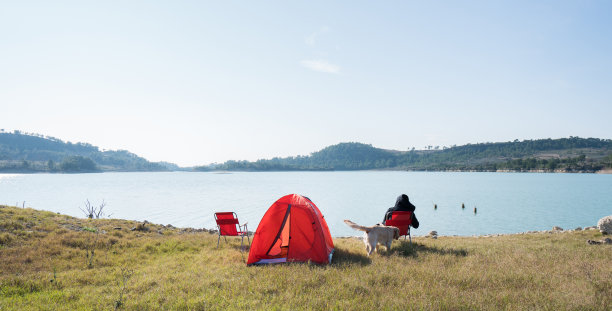 一个女人和她的狗在湖边露营图片下载