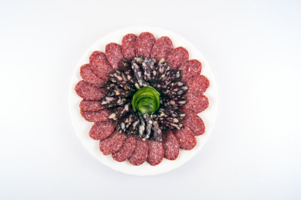 两种切成薄片的香肠放在饰有黄瓜花的白色盘子上图片下载