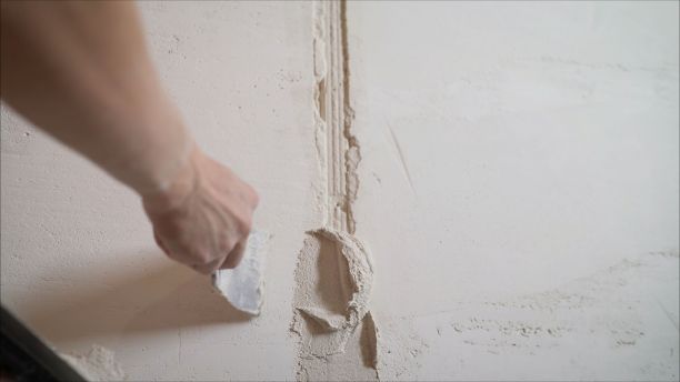 建筑工人用长镘抹墙。混凝土的特写。工人用灰泥堵住白色墙壁上的裂缝。图片下载