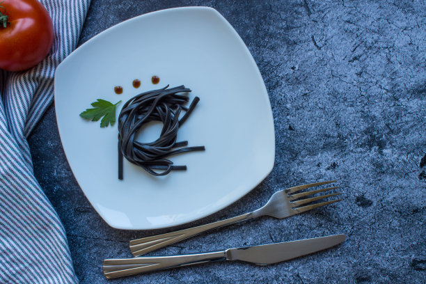 黑色的墨鱼墨糊在白色的方形盘子上图片下载