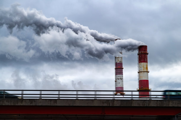 黑色有毒烟雾从工厂的烟囱里冒出来，笼罩在汽车上。旧工业发电厂造成的空气污染和全球变暖图片下载