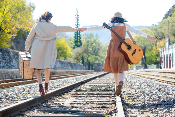 青年闺蜜手牵手走在铁轨上素材图片