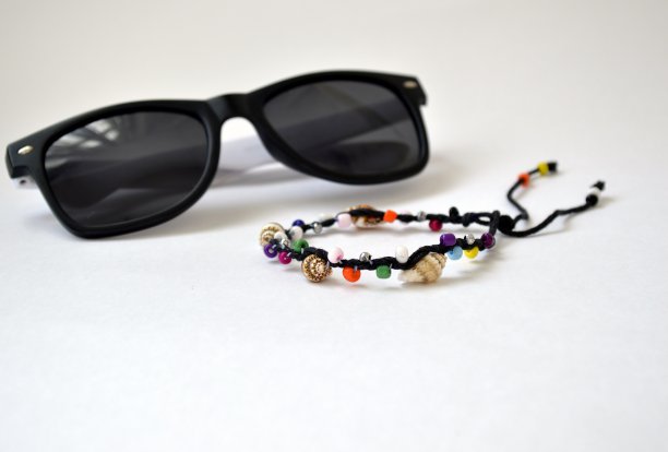 由南海的多色珠子和越南贝壳制成的手工手镯，孤立在白色背景和模糊的太阳镜上图片下载