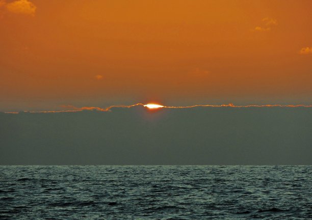 大西洋上空令人愉快的日出。清晨的海浪。天空温暖的颜色。明亮的云。图片下载