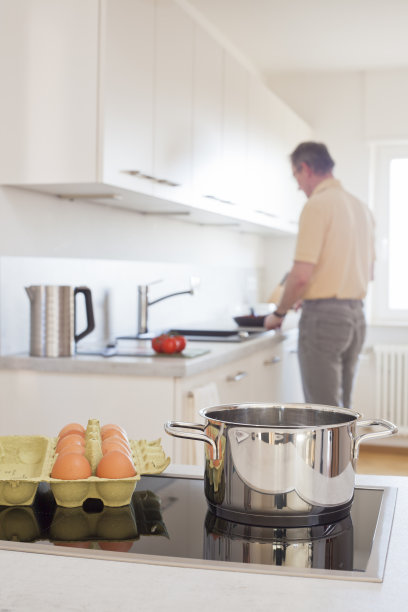 一个在白色厨房里准备鸡蛋的成熟男人图片下载