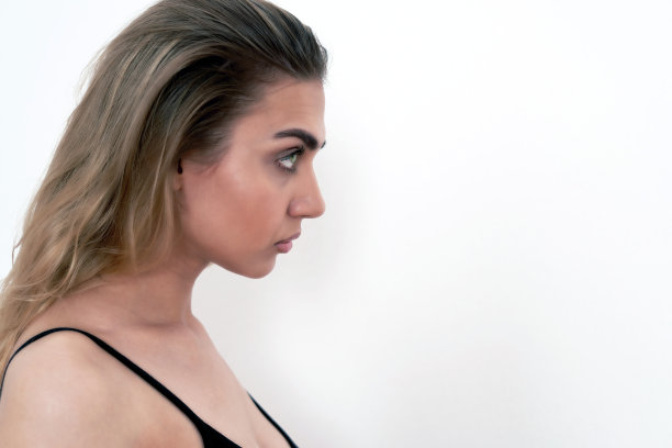 一个美丽的年轻金发碧眼的特写肖像，在侧面，白色的背景。他目不转睛地盯着前方。文本的地方图片下载