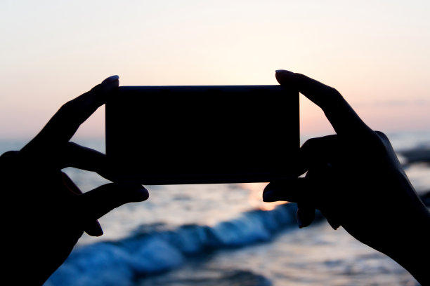 女孩正在用手机拍日落照片图片下载