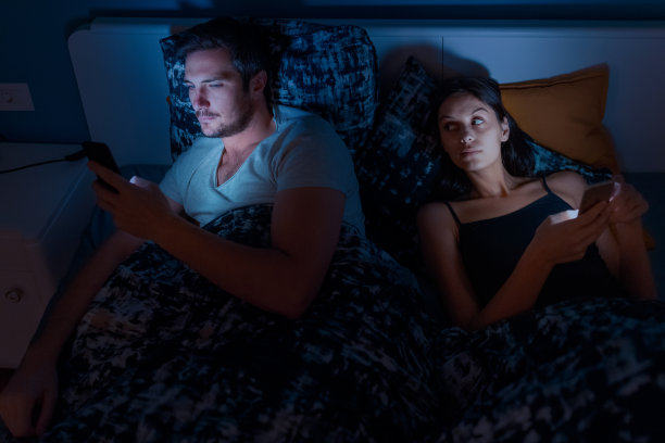 夫妻晚上在床上玩手机，女人用怀疑的目光看着图片下载