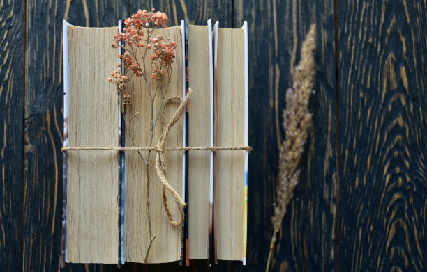一堆用麻绳和干花捆起来的书，放在深色的木制背景上。前视图。特写镜头。平的。图片下载