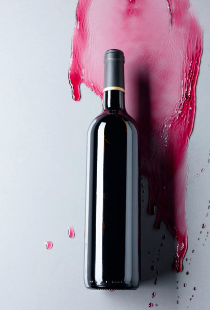 在灰色的背景下，封闭的红酒和流动的葡萄酒。素材图片