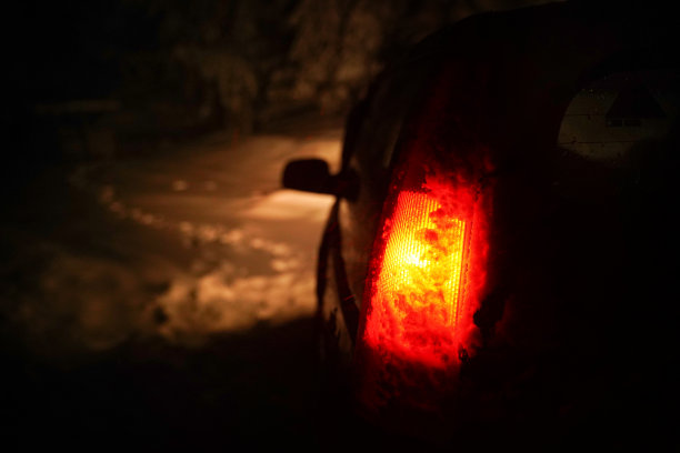 晚上，POV在积雪覆盖的道路上行驶，初雪飘落。红灯照亮一切。图片下载