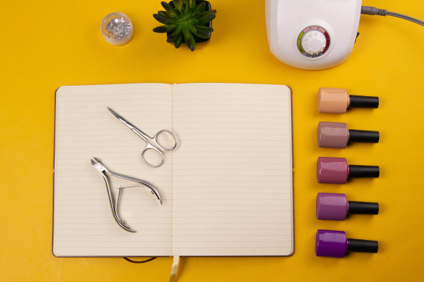 一套美容工具的美甲和足疗在一个橙色的背景。附近有一个打开的笔记本，用来写字，涂胶，磨指甲，剪刀和镊子图片下载