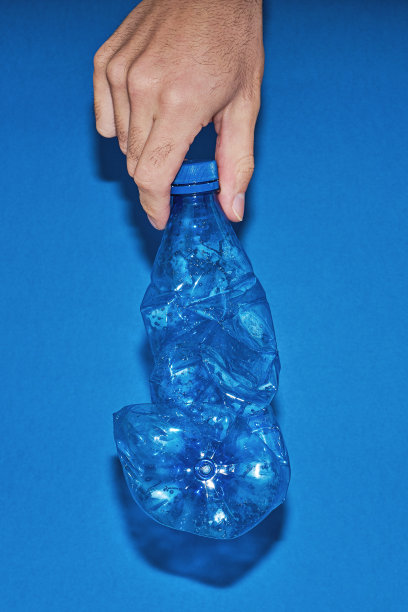 手持蓝色背景上的挤压塑料瓶。“零浪费”的概念图片下载