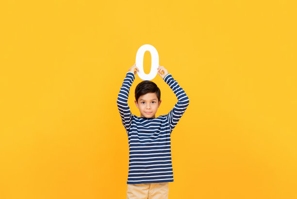 小男孩在黄色背景上显示数字0图片下载