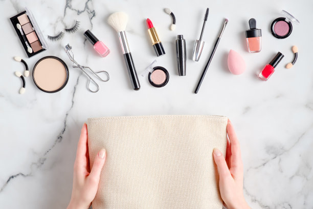 女性手上的化妆包和化妆品溢出到大理石桌上。平躺，俯视图。美丽与时尚概念图片下载