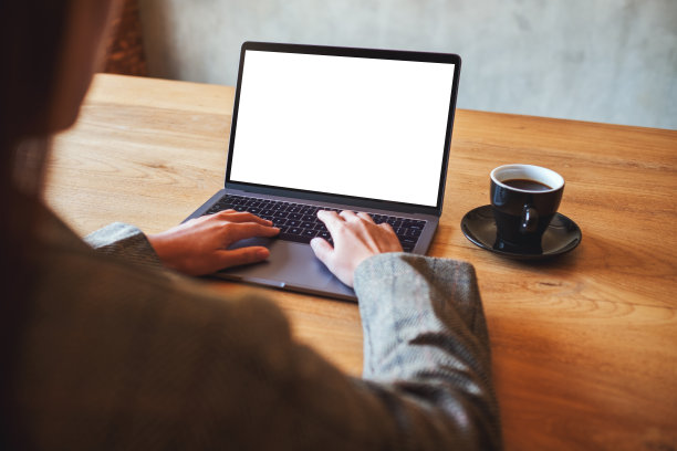 在咖啡馆里，一位女士使用笔记本电脑打字，屏幕显示空白白色桌面图片下载