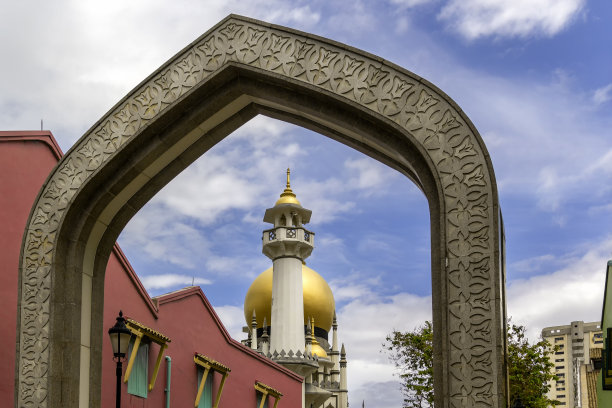 透过蓝色多云的天空背景上的东方风格装饰的拱门，可以看到清真寺的圆顶图片下载