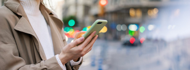 女性手与智能手机的特写照片。夜晚的街道背景图片下载