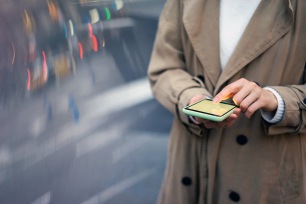 女性手与智能手机的特写照片。夜晚的街道背景图片下载