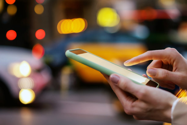 女性手与智能手机的特写照片。夜晚的街道背景图片下载