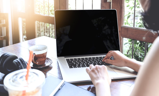 一名年轻女性坐在咖啡馆里使用笔记本电脑的镜头。图片下载