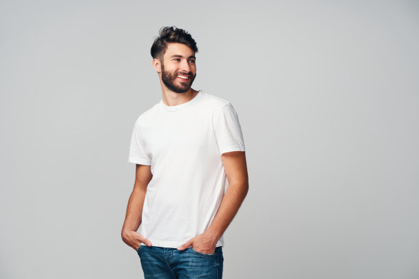 英俊的年轻人微笑孤立在灰色背景穿着休闲t恤和牛仔裤看向别处图片下载