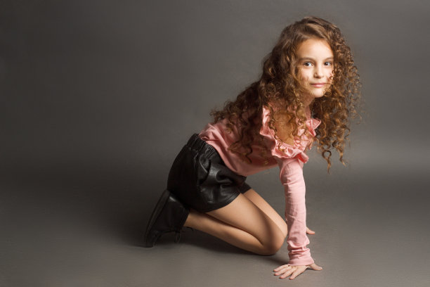 小女孩穿着粉色衬衫和紧身短裤灰色背景图片下载