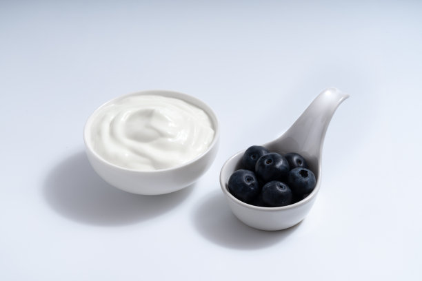 天然自制的纯有机酸奶与新鲜的蓝莓水果混合在白色的碗，在白色的背景，复制空间图片下载