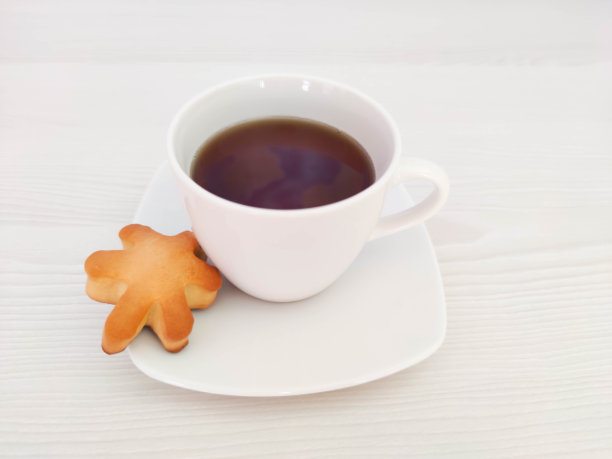 一杯白色的茶或咖啡，在有复印空间的木桌上放一碟饼干。一张为café或餐厅菜单或包装背景的照片。图片下载