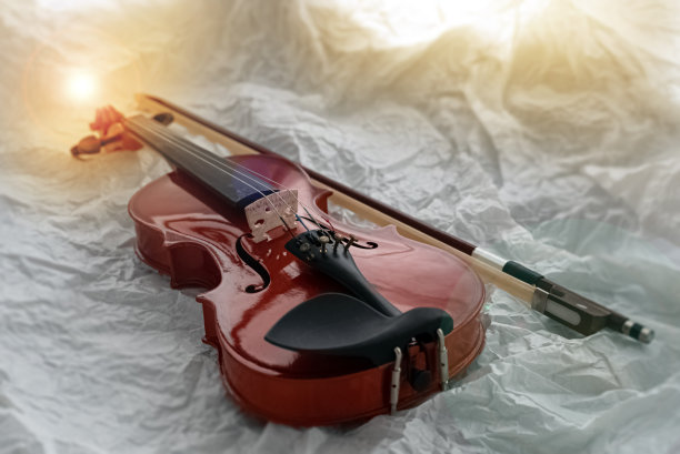 小提琴和琴弓以垃圾表面为背景，镜头光晕效果，复古色调，四周模糊的灯光图片下载