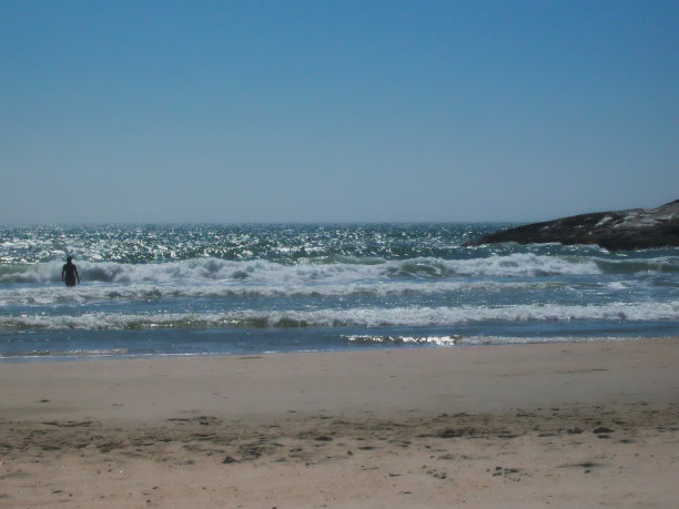 在费鲁格姆海滩的蔚蓝无云的天空下，有狭长的沙滩和波光粼粼的海浪。图片下载